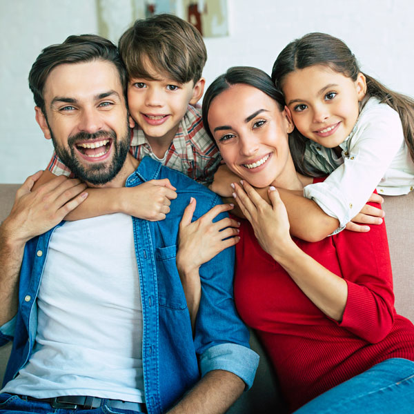family of four smiling together on the couch